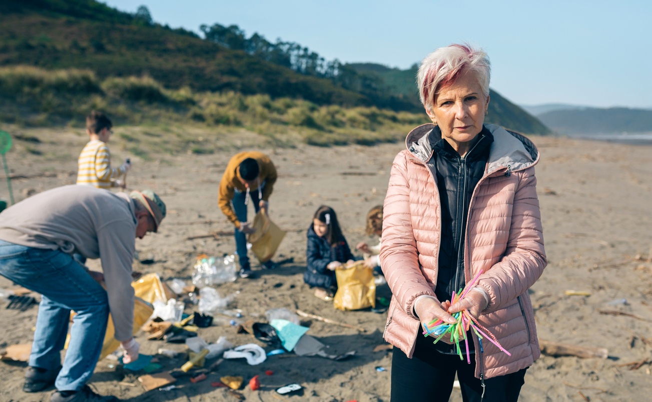 A woman holding straws she picked up on the beach with other volunteers