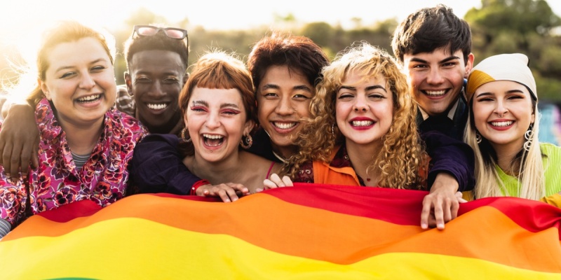 Variety of people holding pride flag